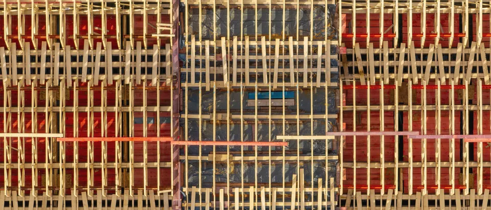 Bekisting kayu dan baja merah dilihat dari atas, seperti pola garis